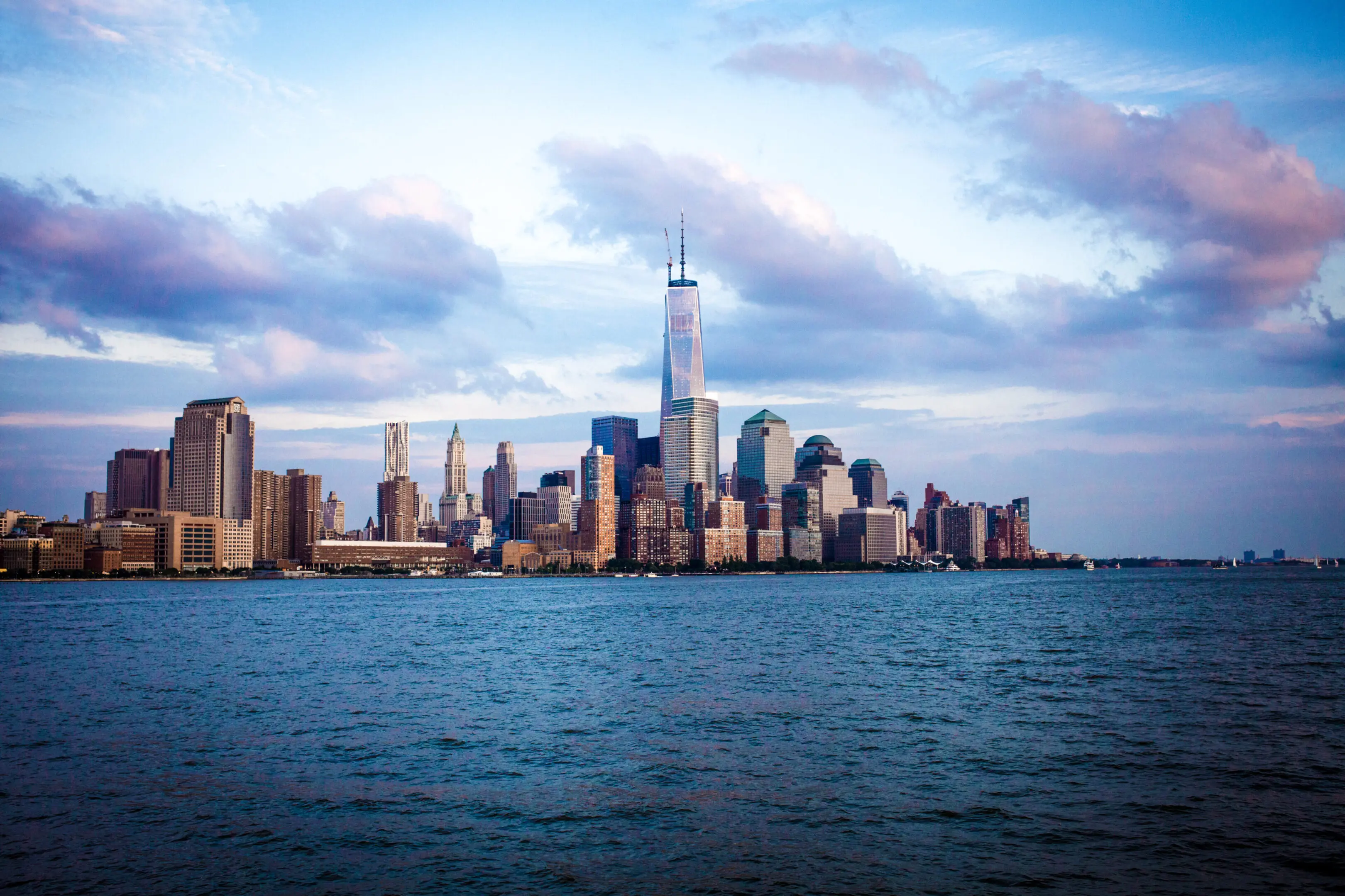 Skyline of New York City with the One World Trade Center under a cloudy sky.